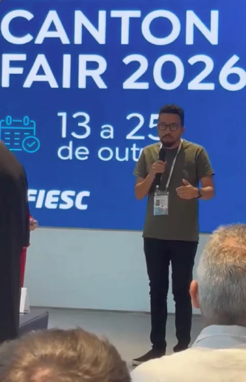 André Ricardo fala ao microfone diante do painel Canton Fair 2026